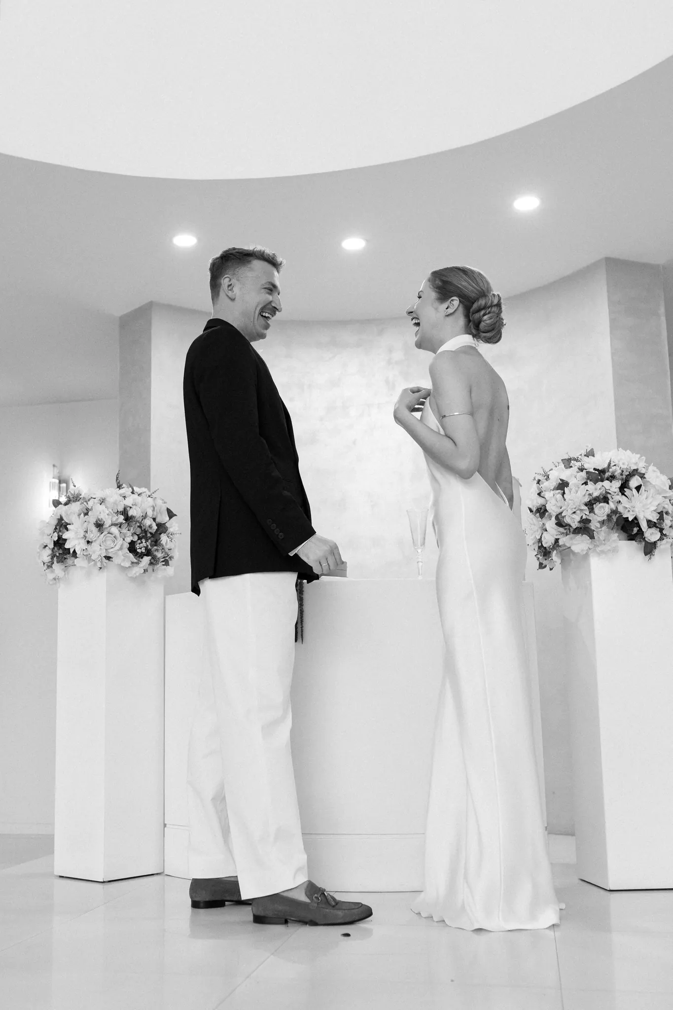 Veronika and Sasha laughing at the ceremony table, black and white