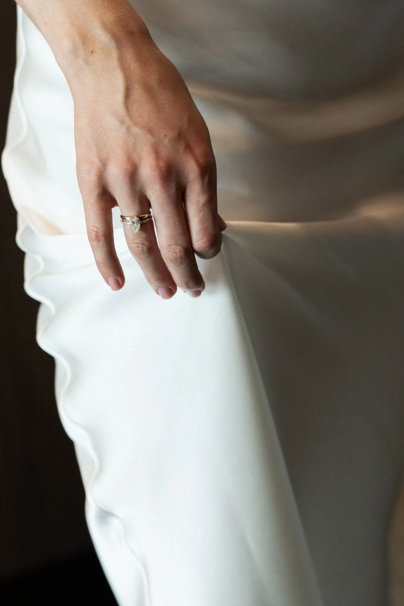 Veronika’s hand with her rings against the satin of her dress