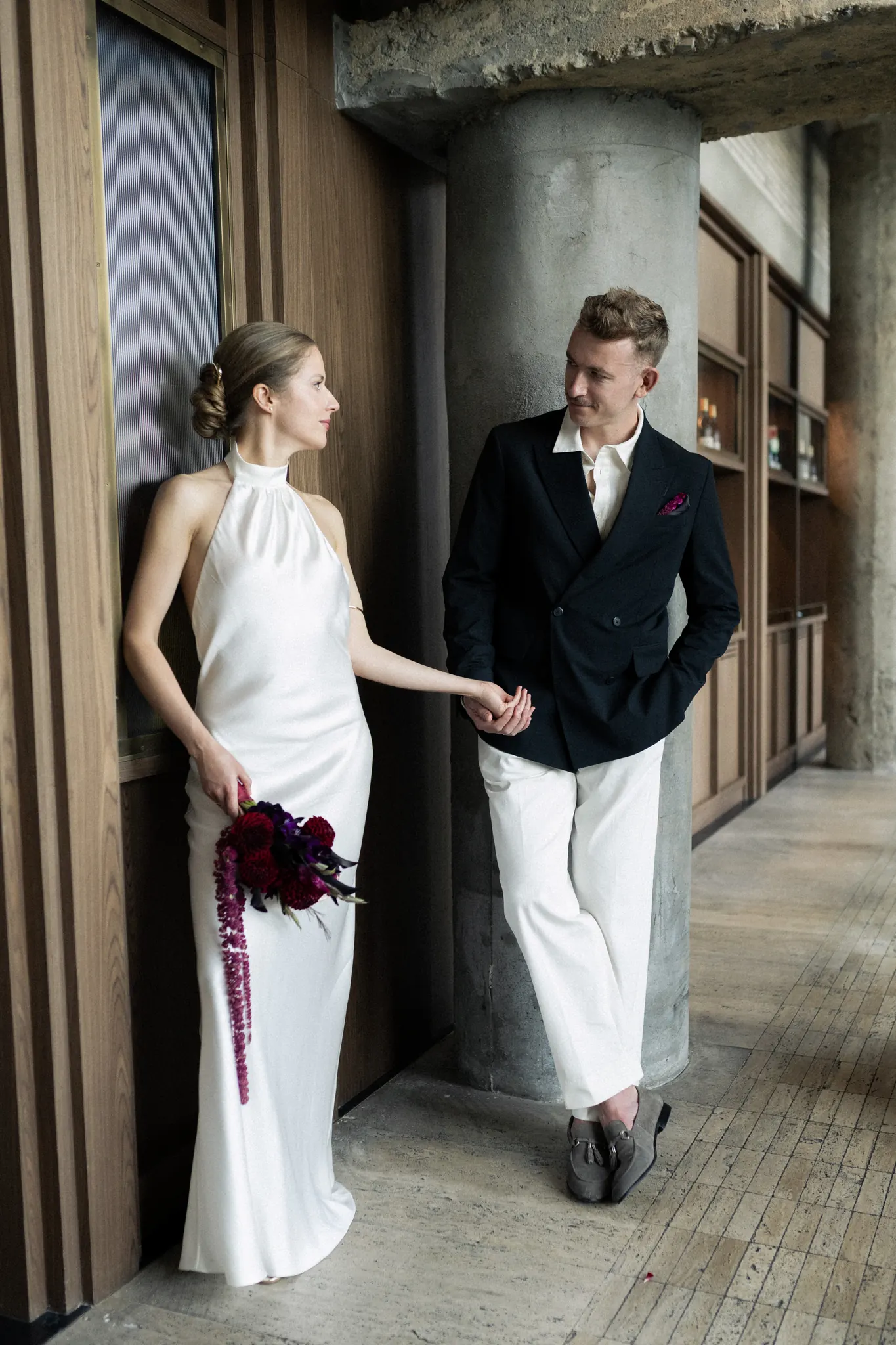 Veronika and Sasha holding hands by a concrete column