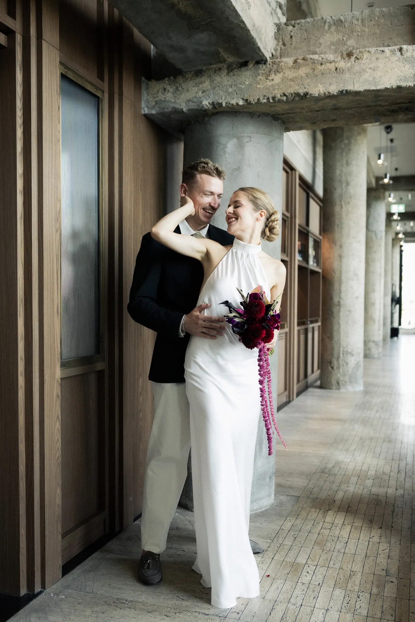 Veronika and Sasha laughing together by a concrete column