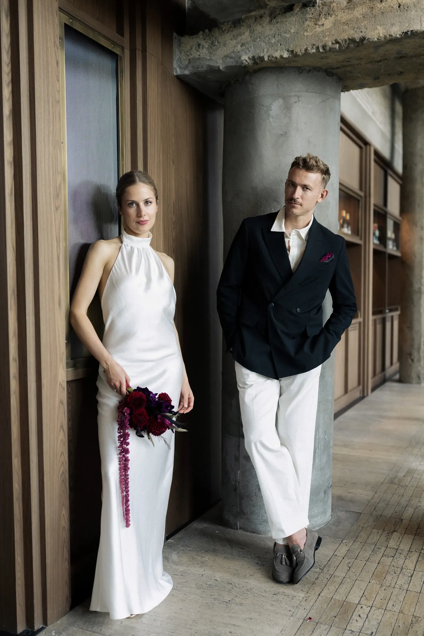Veronika and Sasha leaning against the wall and the column, looking at the camera
