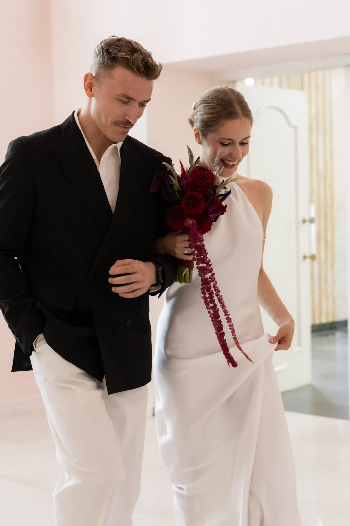 Veronika and Sasha walking side by side, Veronika smiling with her bouquet