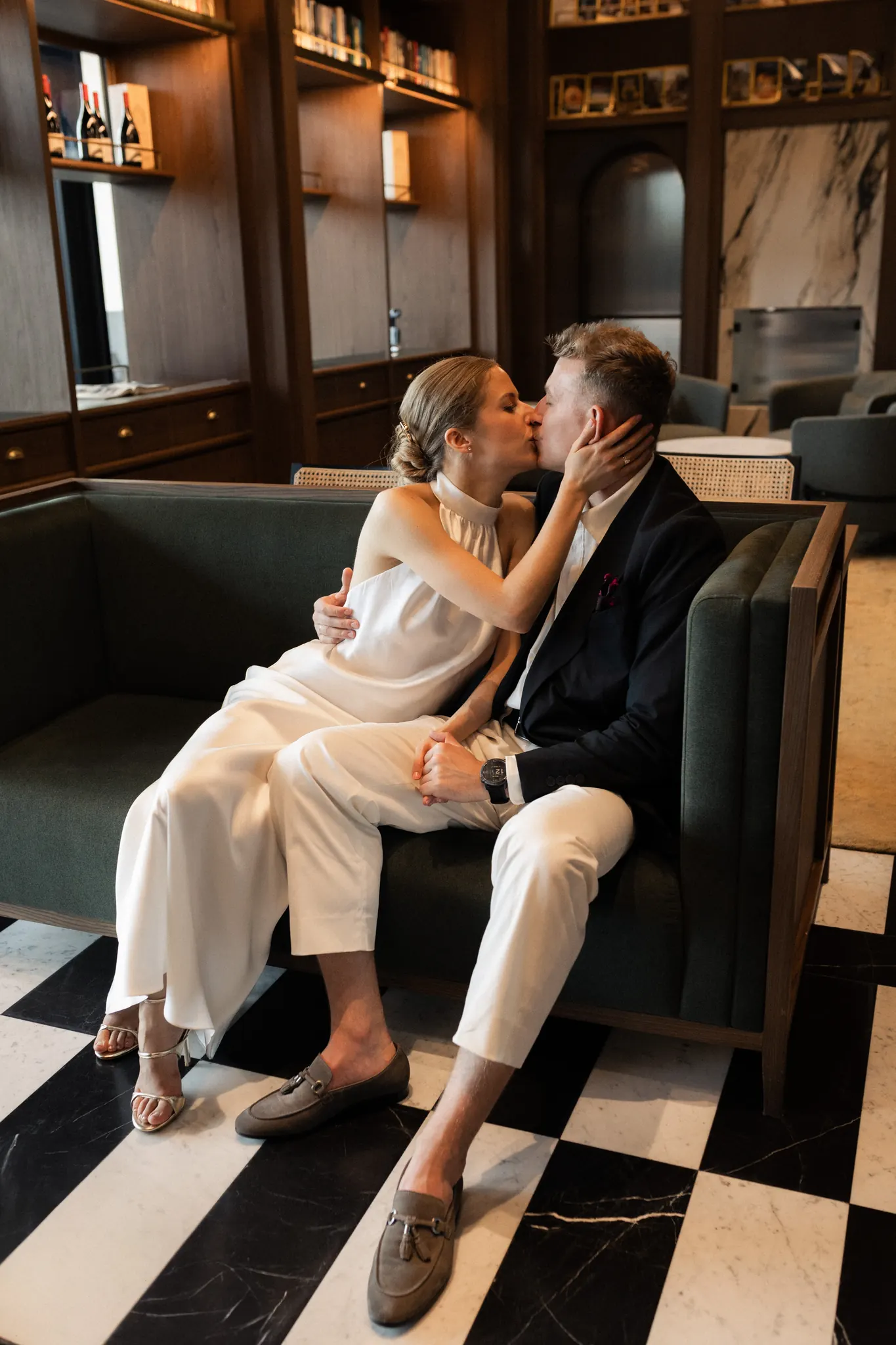 A kiss on the green sofa above a checkerboard floor