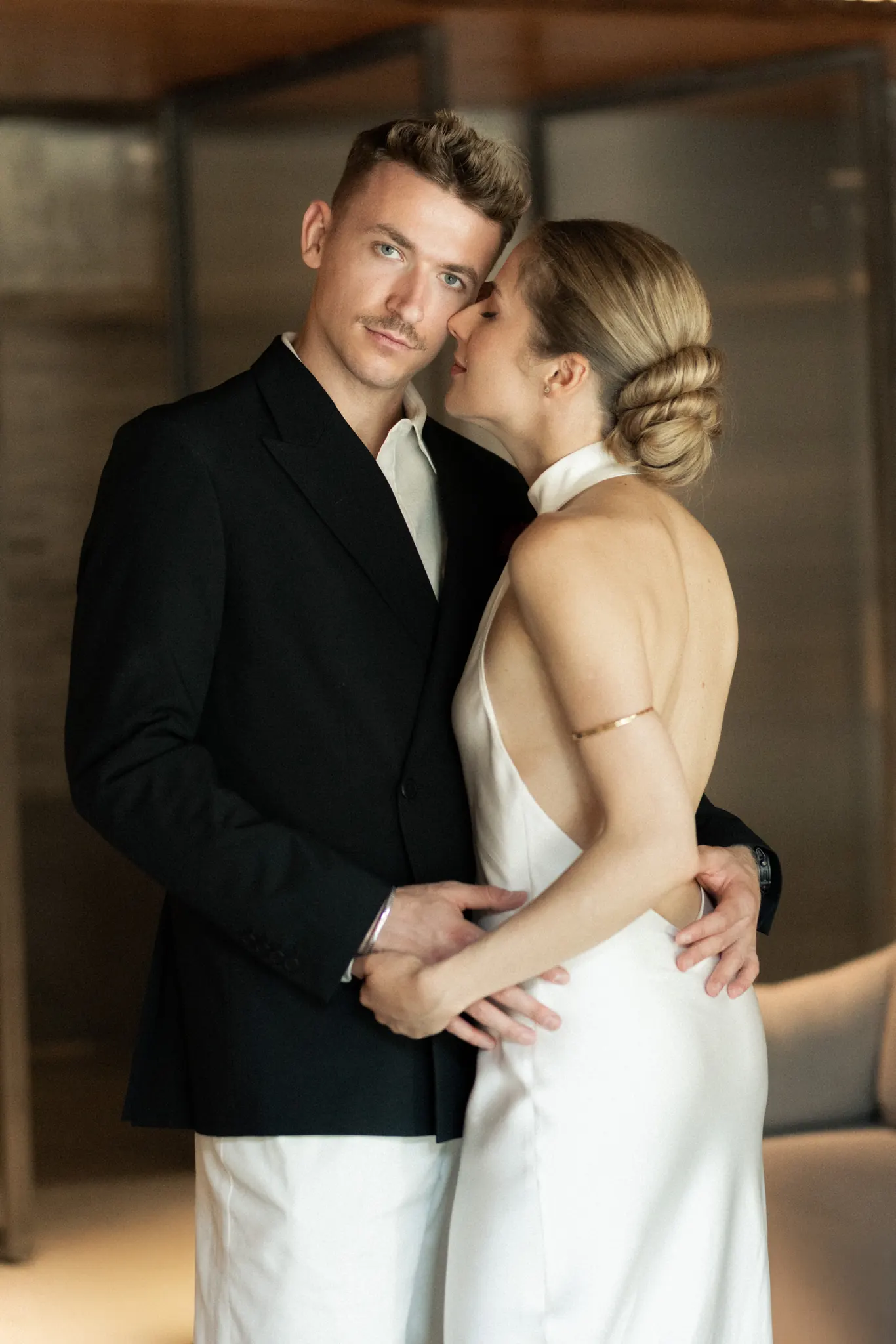 Veronika leaning into Sasha as he looks at the camera