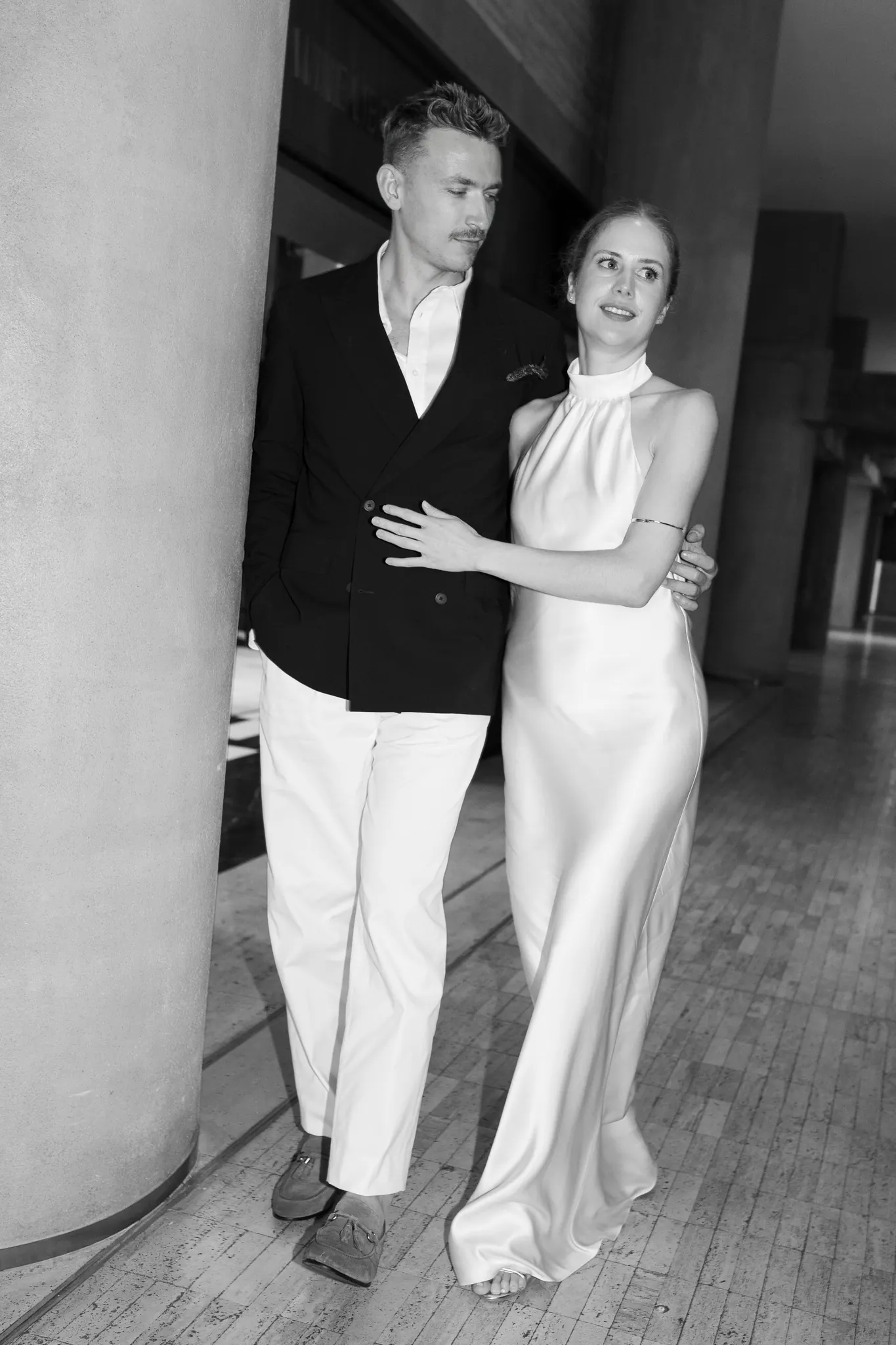 Veronika and Sasha walking past a concrete column, black and white