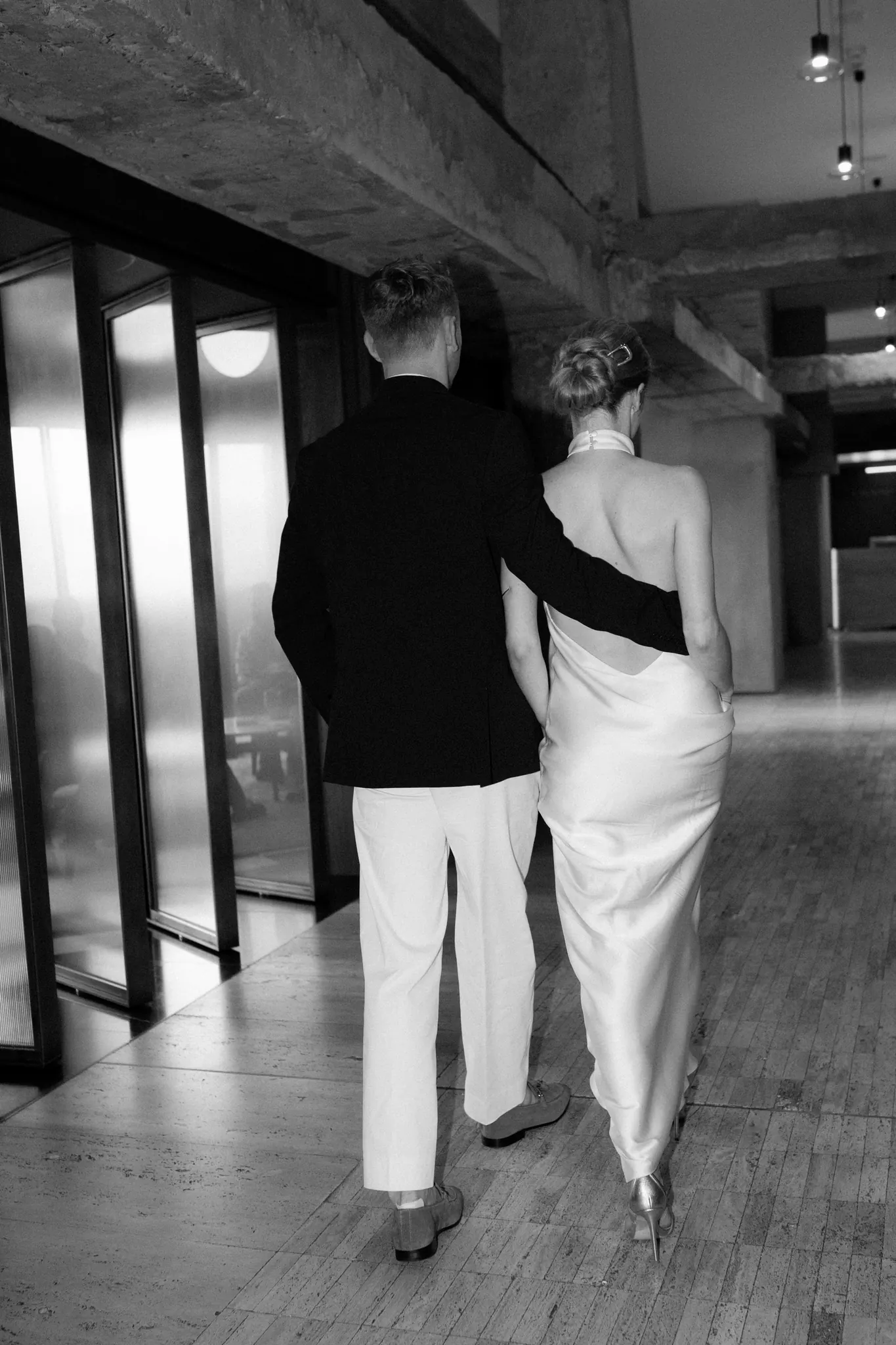 Veronika and Sasha walking away down a corridor, black and white