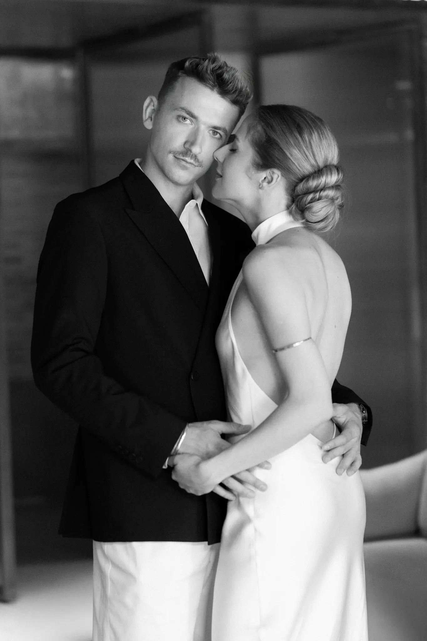 Veronika leaning into Sasha as he looks at the camera, black and white