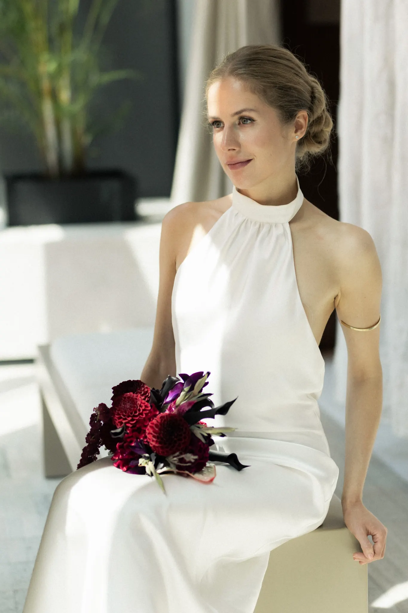 Veronika seated in soft daylight, her bouquet on her lap