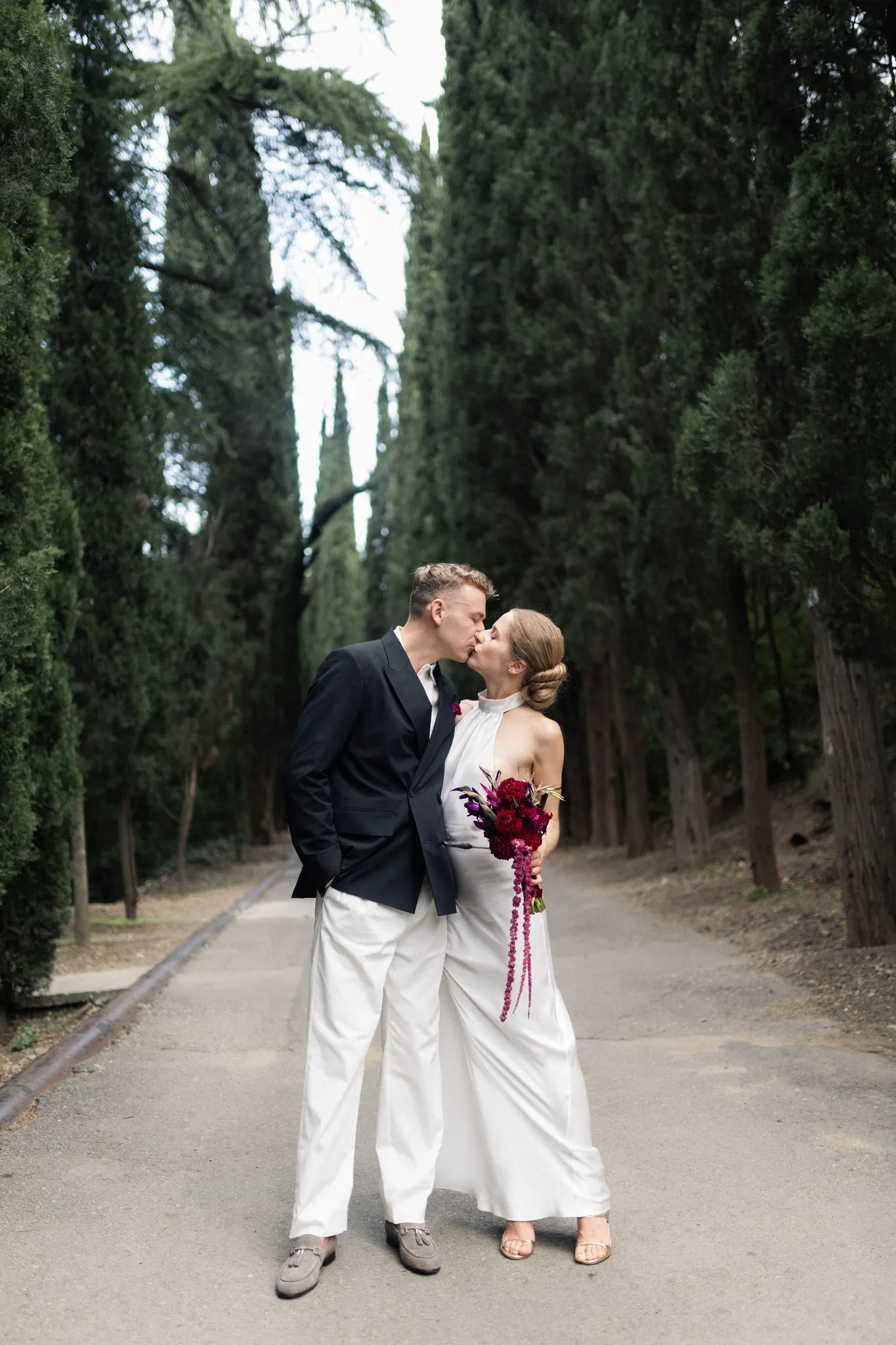 A kiss in an alley of cypress trees